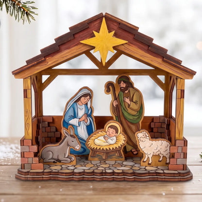 Painted laser cut plywood Nativity stable scene with Holy Family figures on table beside snowy pine branches and ornaments.