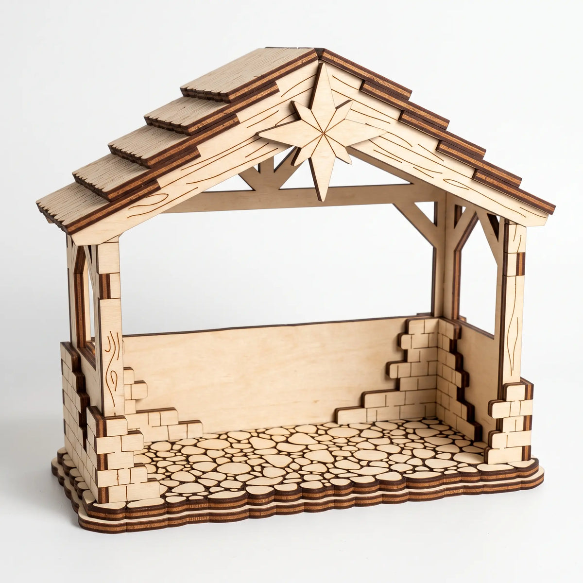 Empty laser cut plywood Nativity stable with shingle roof, carved star, and stone floor details on plain white background.