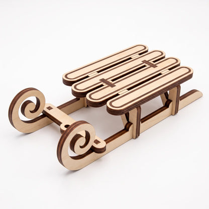 Perspective view of assembled laser cut plywood vintage holiday sled with slotted runners on white backdrop
