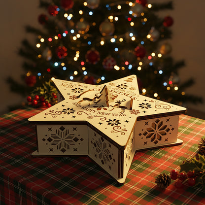 Delicate laser cut Christmas Star Box featuring festive cut-out designs of bells, stars and holiday greetings on a five-pointed star shape, set against a warm blurred Christmas tree glow background.