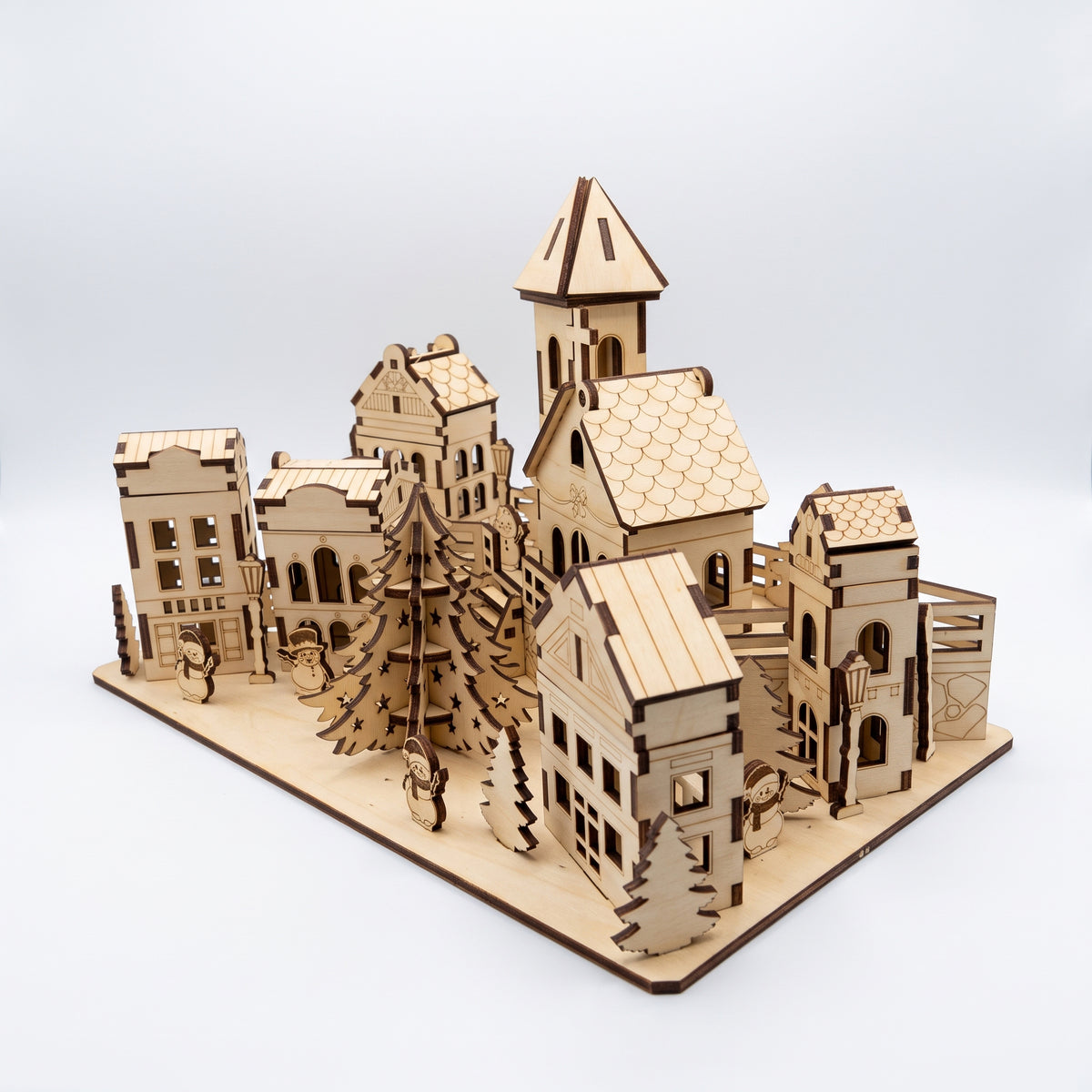 Elevated side-angle view of assembled laser cut plywood Christmas town diorama with church tower and houses on white