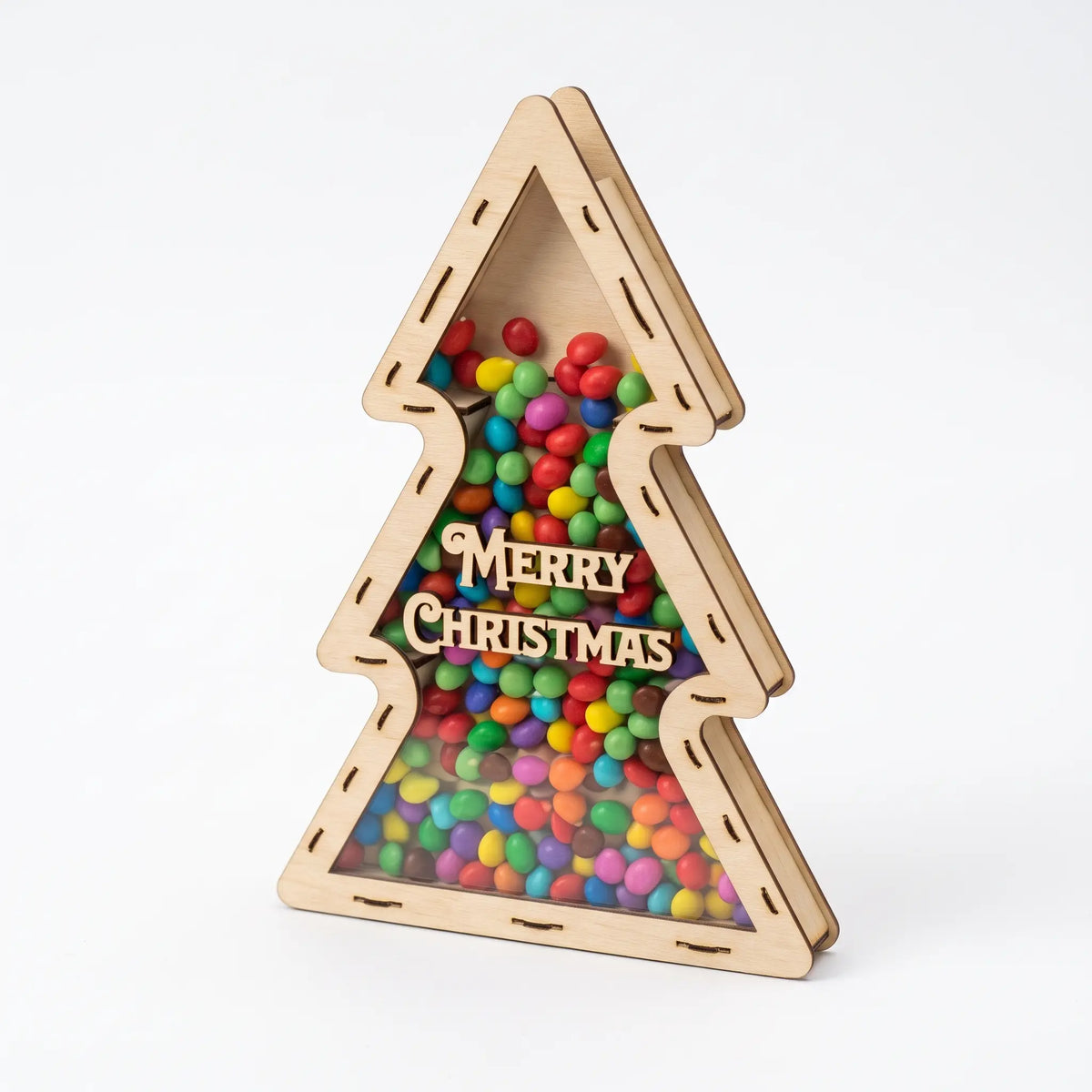 Side view of laser cut plywood tree candy box with clear acrylic front, filled with chocolate buttons on white.
