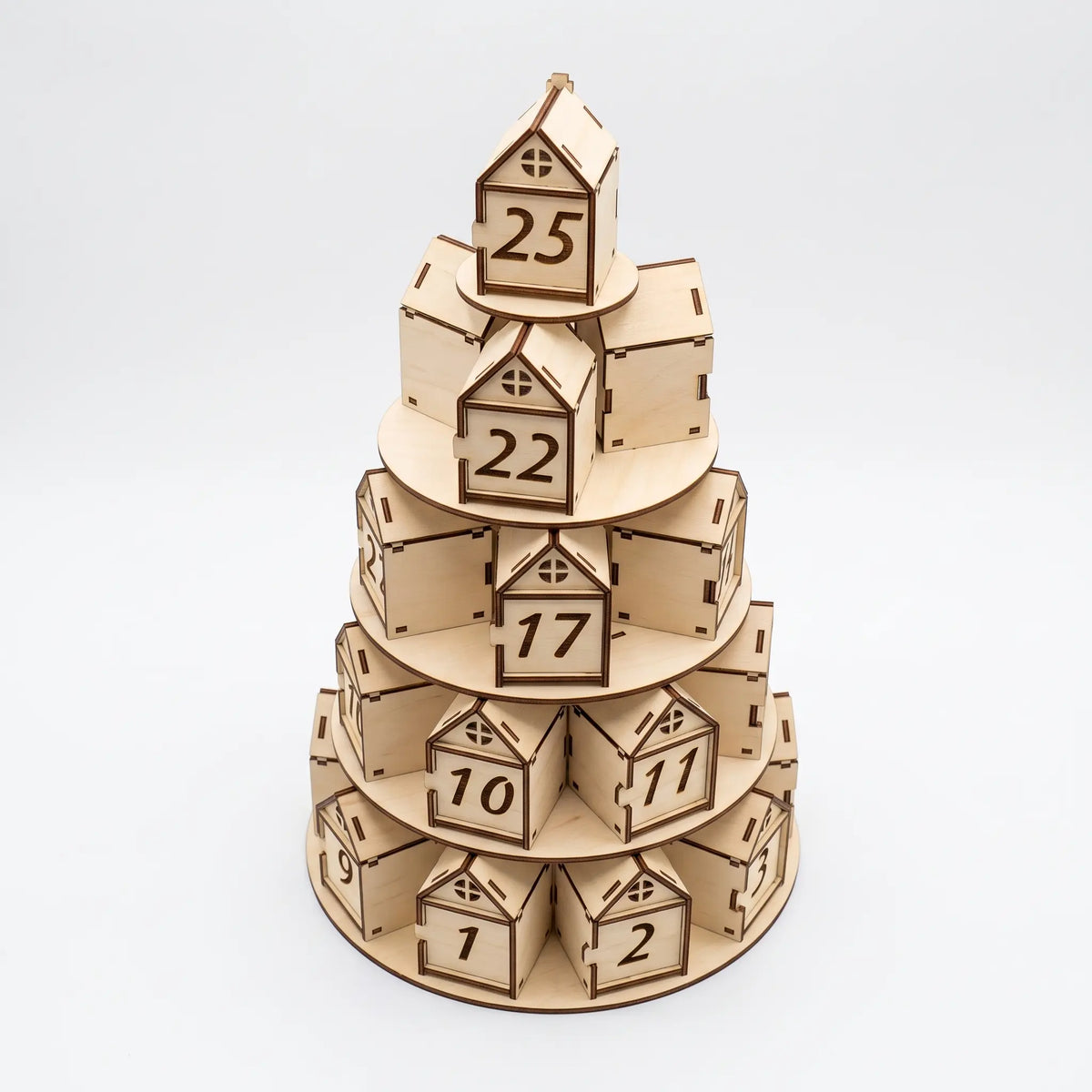 Front view of tiered laser cut plywood Christmas tree advent calendar with numbered house boxes on white.