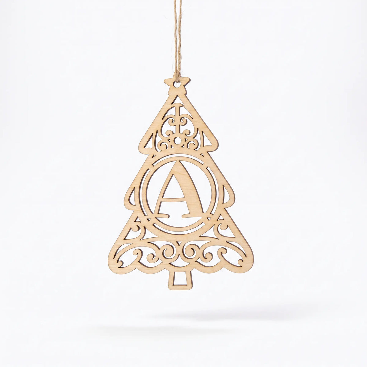 Laser cut plywood Christmas tree ornament with letter A monogram and ornate filigree swirls hanging against white background.