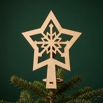 Natural laser cut plywood snowflake star tree topper mounted on Christmas tree branch against a dark green backdrop.