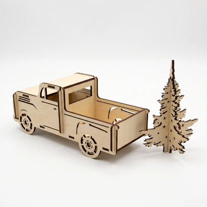 Rear three-quarter view of empty laser cut plywood vintage pickup truck standing beside cutout pine tree on white