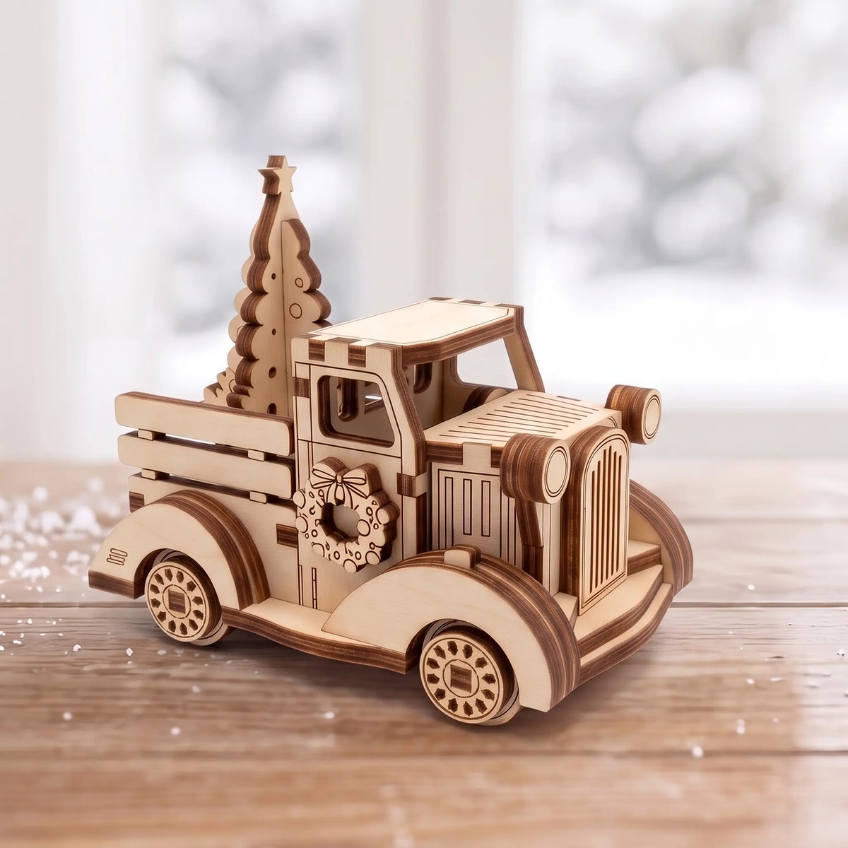 Vintage laser cut plywood holiday pickup truck carrying Christmas tree on wooden table in front of bright snowy window.