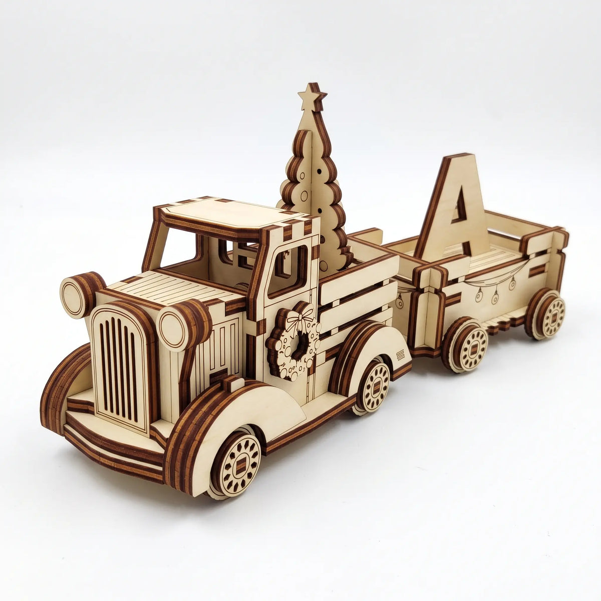 3D laser cut plywood vintage holiday pickup truck carrying a pine tree and trailer with wooden letter A on white background.
