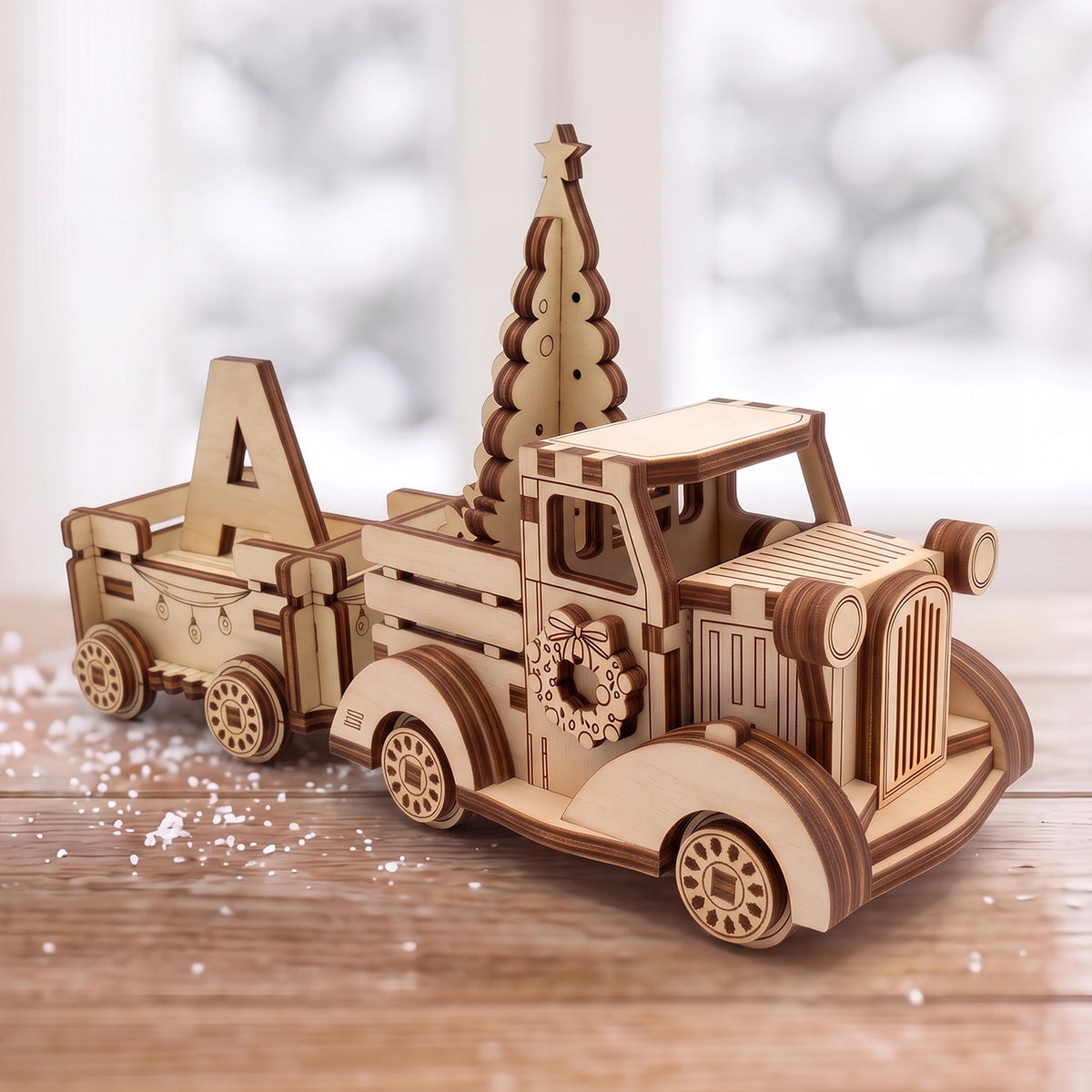 Laser cut plywood vintage Christmas truck with tree and wagon hauling letter A on snowy tabletop near window.