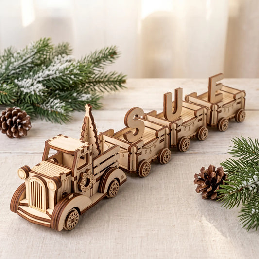 Personalized laser cut plywood Christmas truck train spelling SUE on linen tablecloth beside pine cones and evergreen fir.