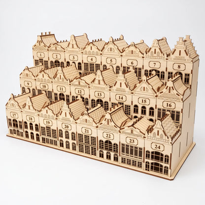 Front three-quarter view of tiered laser cut plywood Christmas town advent calendar with detailed building facades.