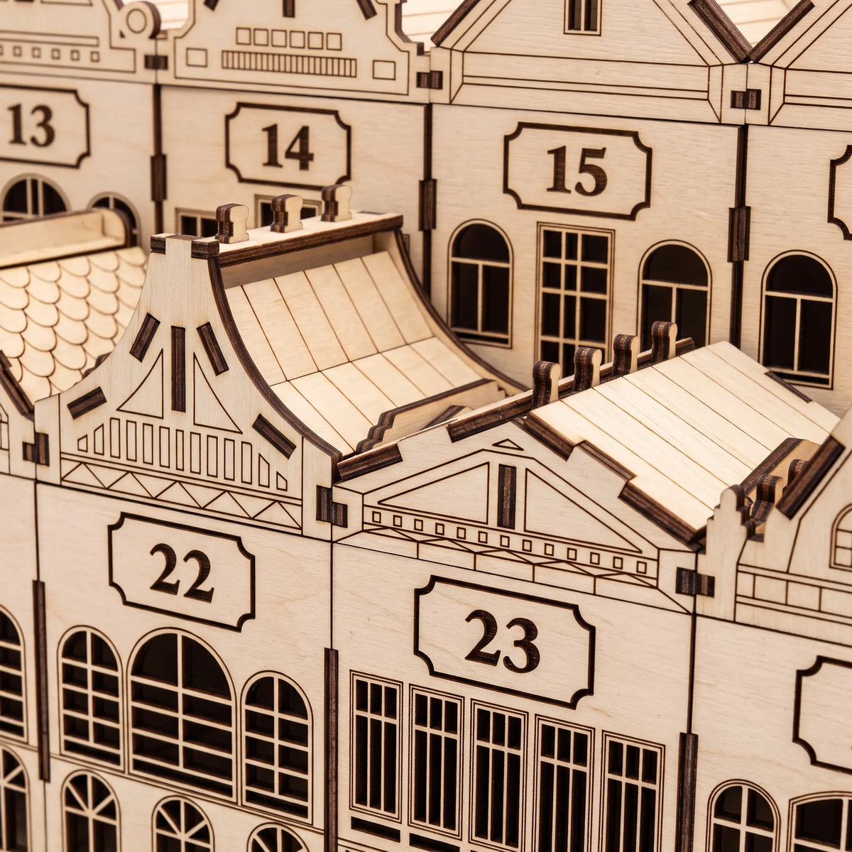 Close-up of laser cut plywood advent calendar drawers showing engraved windows, gable trim, and numbered plaques