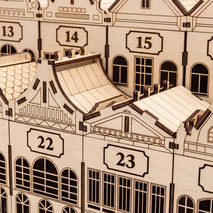 Close-up of laser cut plywood advent calendar drawers showing engraved windows, gable trim, and numbered plaques