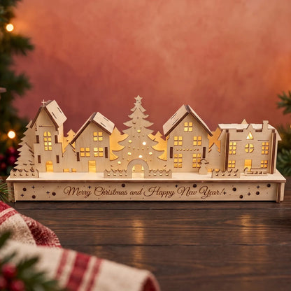 Illuminated laser cut plywood holiday village diorama glowing on dark wood table next to cozy lantern.