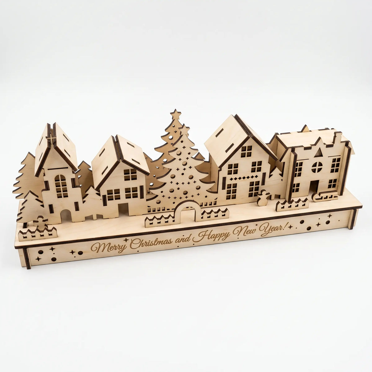 High angle view of laser cut plywood winter village with holiday greeting on wooden base isolated on white.