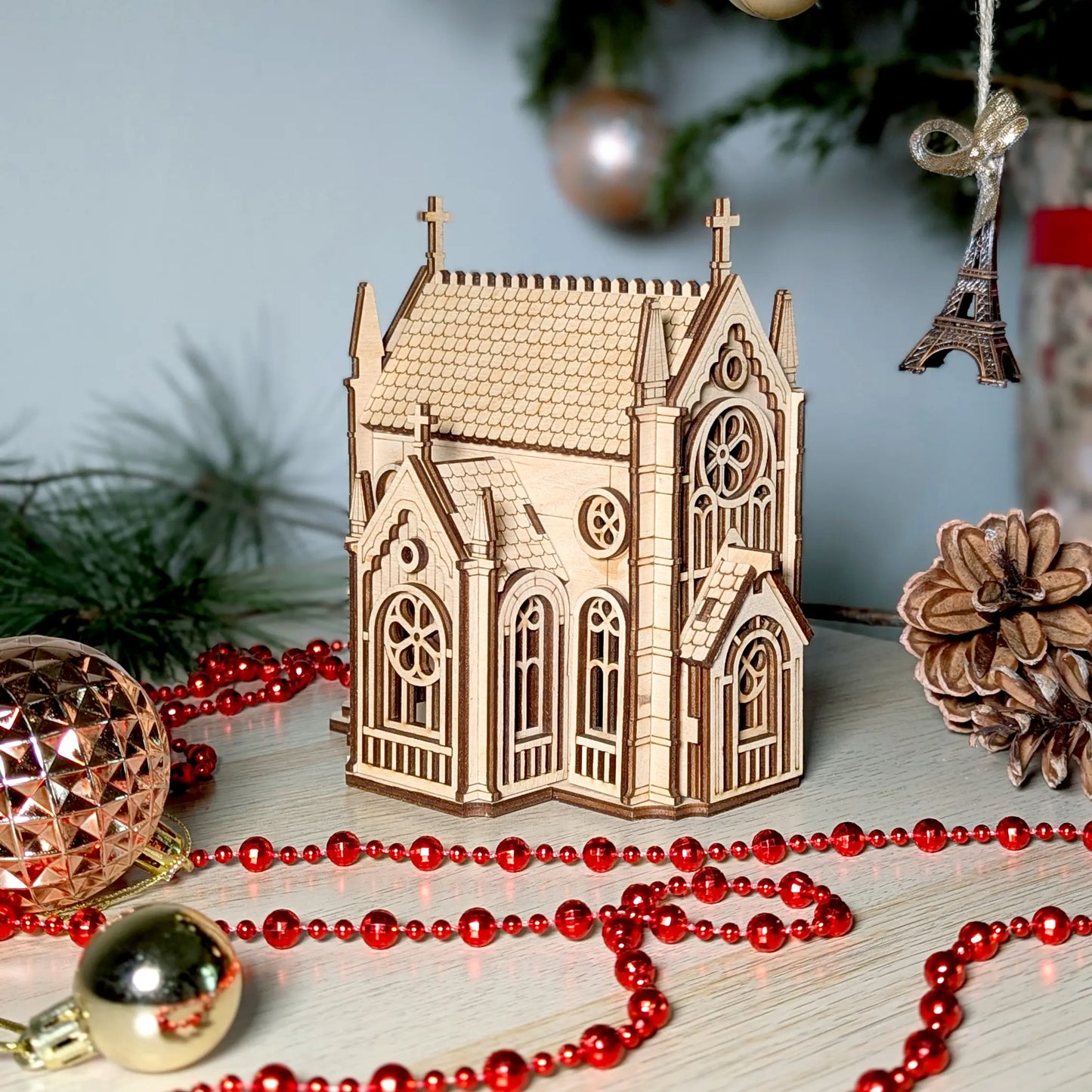 A festive Christmas product staging shot of a miniature tabletop gothic cathedral puzzle made from laser cut plywood.