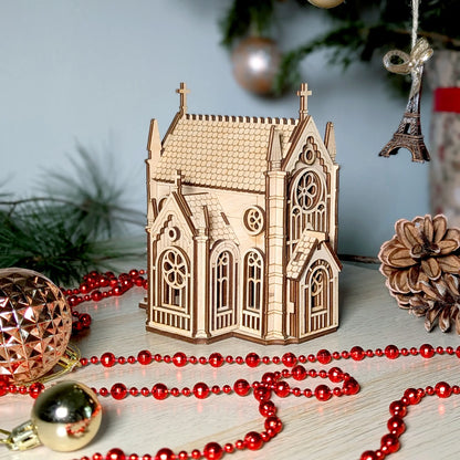 A festive Christmas product staging shot of a miniature tabletop gothic cathedral puzzle made from laser cut plywood.