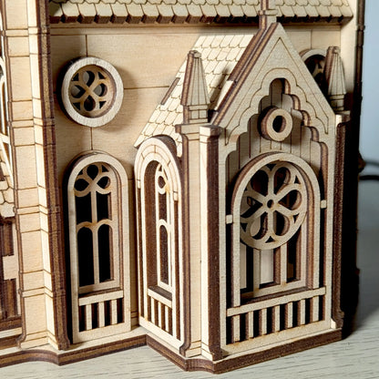 Macro close-up shot focusing on the delicate arched windows and gothic details of a mini laser cut plywood cathedral.