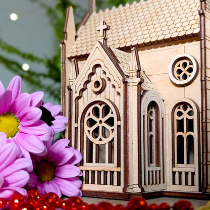 Beautiful close product shot of a miniature church model styled with bright pink flowers and laser cut plywood layers.