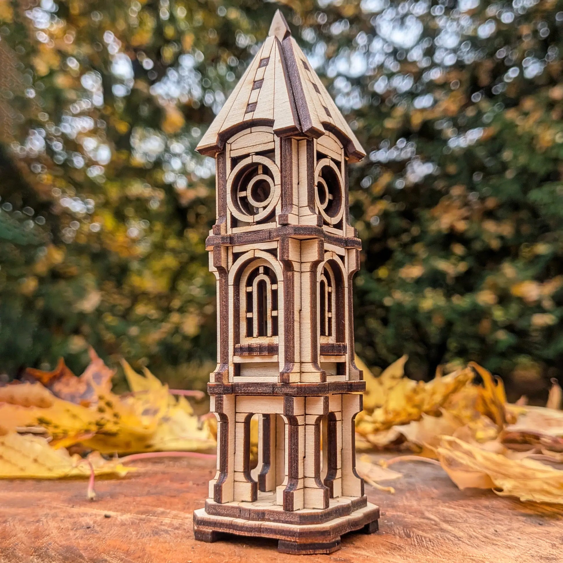 Low-angle scenic view of a detailed miniature architectural clock tower model made of laser cut plywood with forest bokeh