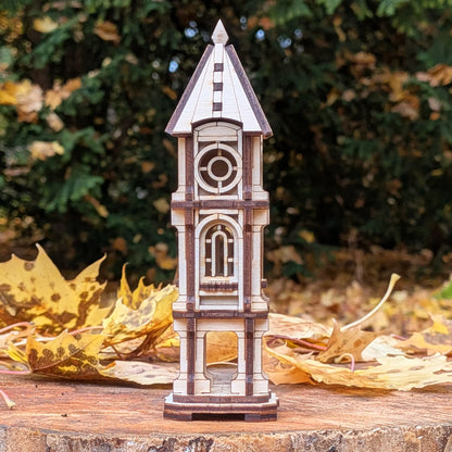 Eye-level straight shot of a miniature architectural clock tower model made of laser cut plywood on an autumn wood stump