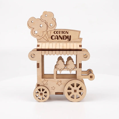 Side profile of 3D laser cut plywood cotton candy cart miniature with spoked wheels and banner on plain white background