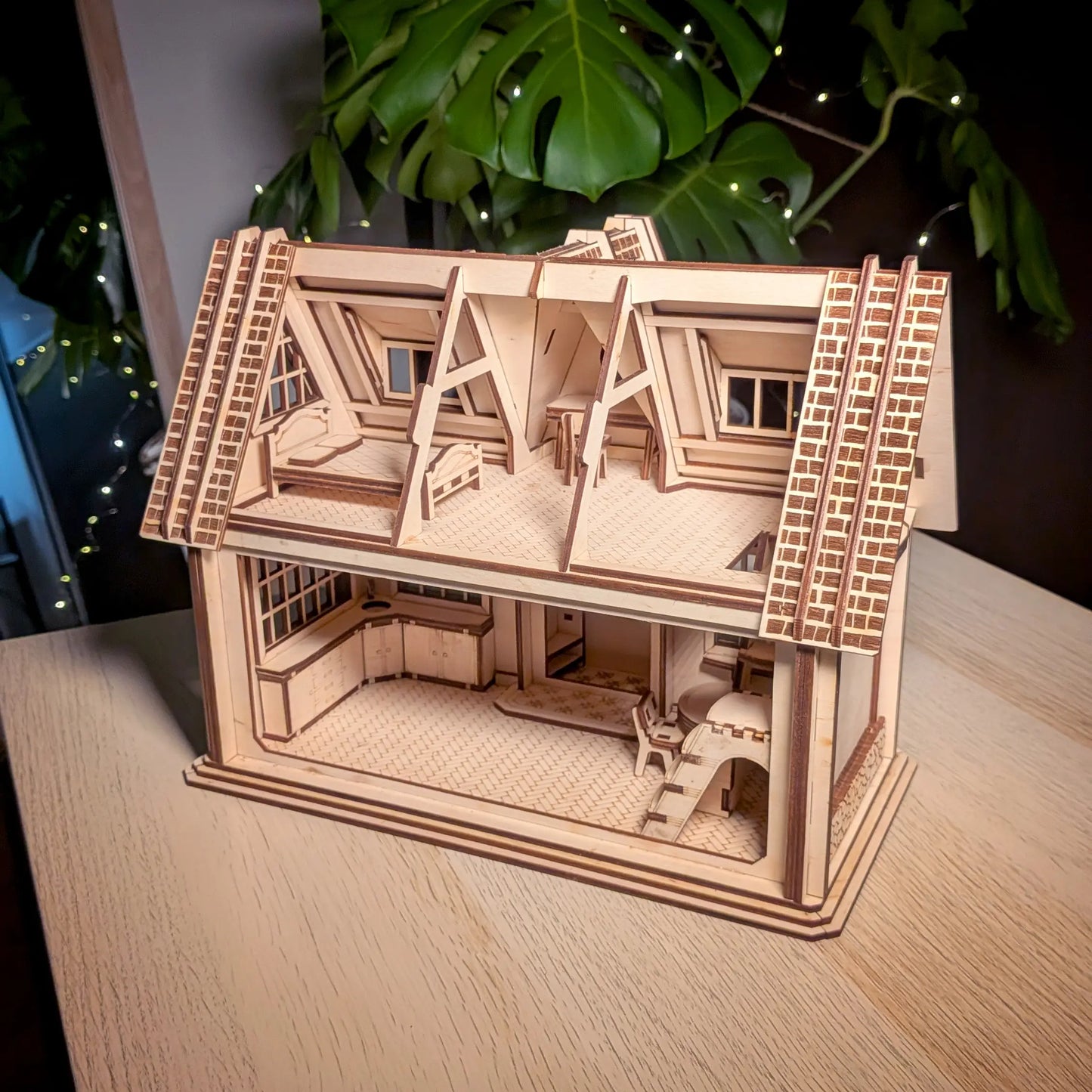High-angle view of an open back laser cut plywood dollhouse model revealing miniature kitchen, wooden stairs, and bedroom