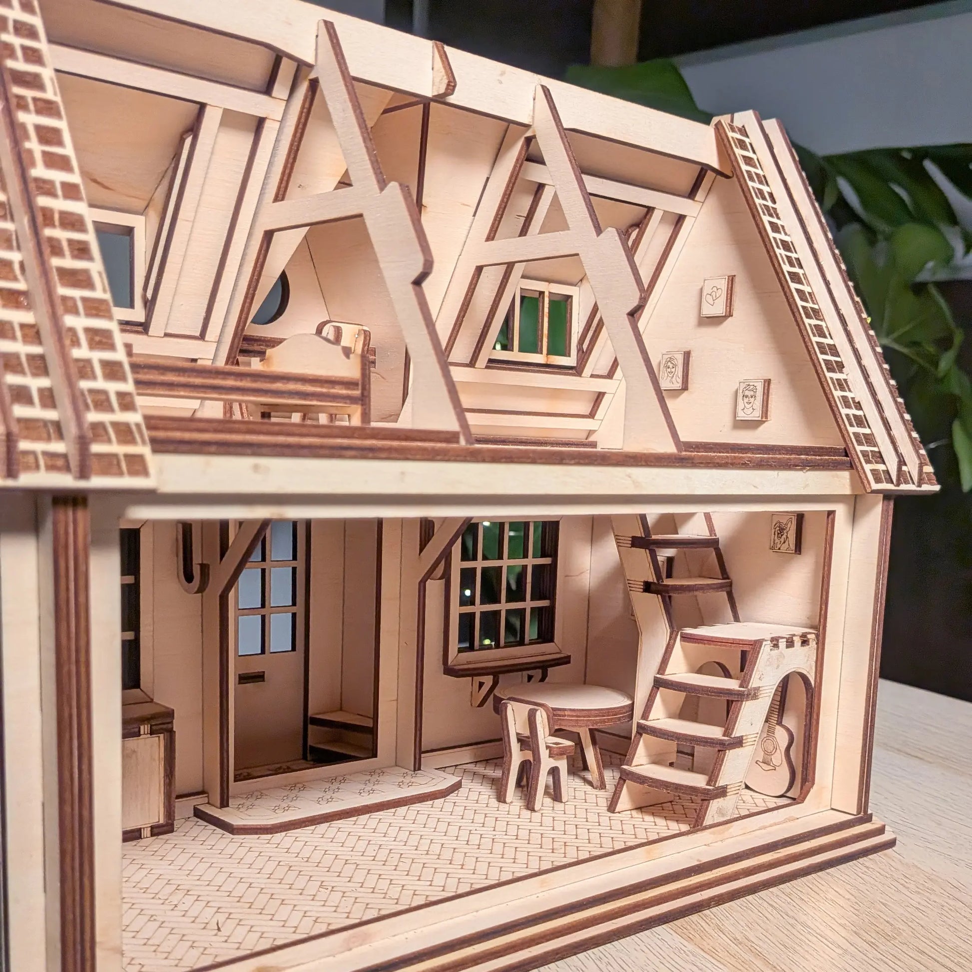 Detailed interior view of a two-story laser cut plywood dollhouse showcasing a miniature table, tiny chairs, and stairs.