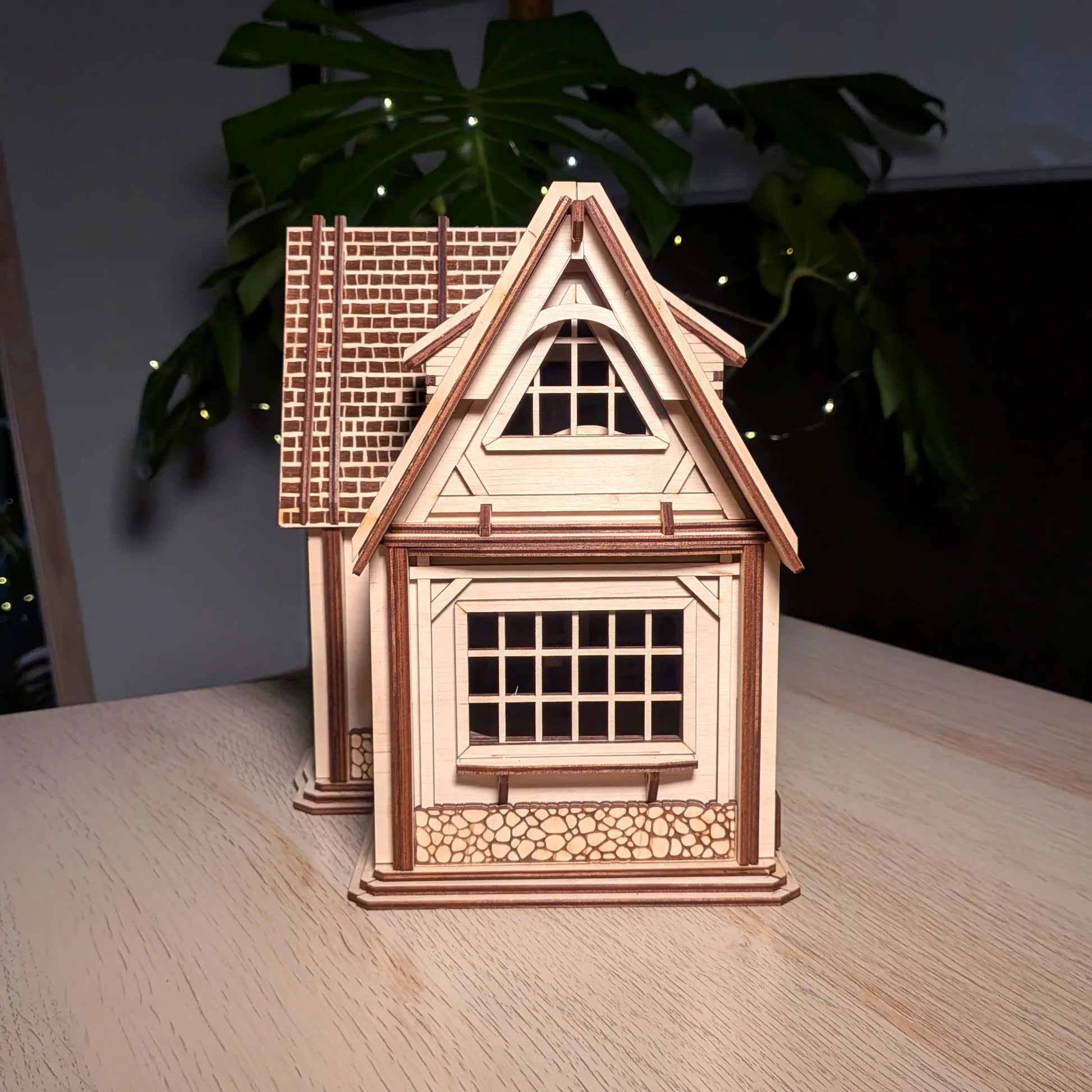 Side profile view of an assembled miniature country dollhouse showing windows and stone-textured laser cut plywood trim.