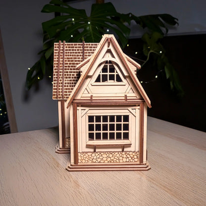 Side profile view of an assembled miniature country dollhouse showing windows and stone-textured laser cut plywood trim.