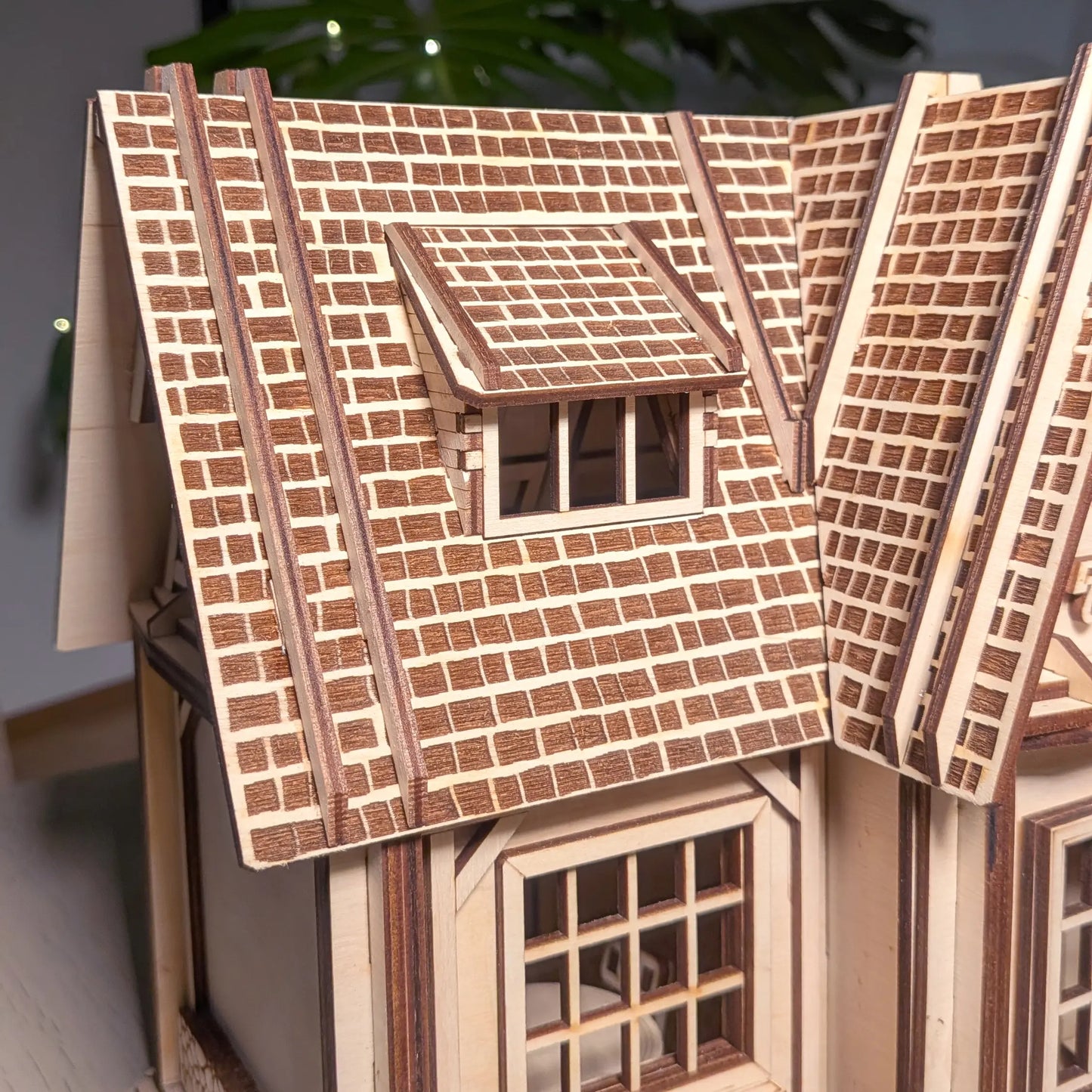 Detailed macro view of engraved brick shingle roof and a dormer window on a miniature laser cut plywood country house.