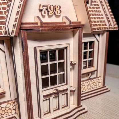Close-up of the front entrance of a laser cut plywood miniature house featuring number 798 and engraved stone base walls.