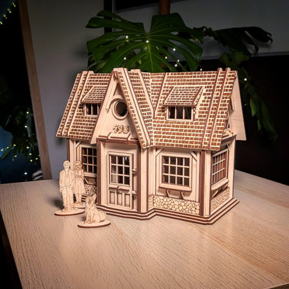 Finished laser cut plywood country house model on a wooden table with tiny family standees and a green leaf backdrop.