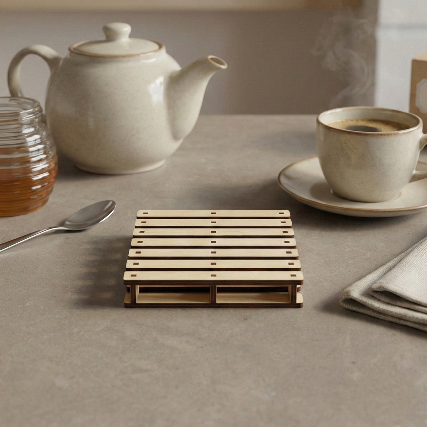 Natural light wood laser cut pallet coaster featuring precise slotted construction and dark accents, displayed on a warm kitchen surface.