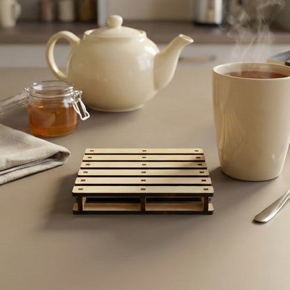Elegant laser cut wooden coaster resembling a tiny pallet, supporting a hot tea mug with vapor, in a serene kitchen environment.