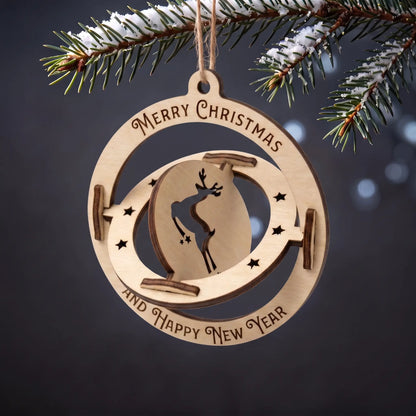 Kinetic laser cut plywood spinning deer bauble ornament with engraved holiday text on snow-dusted fir tree.