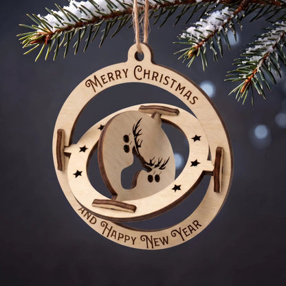 Kinetic laser cut plywood 3D sphere ornament with spinning reindeer center hanging from snowy evergreen branch