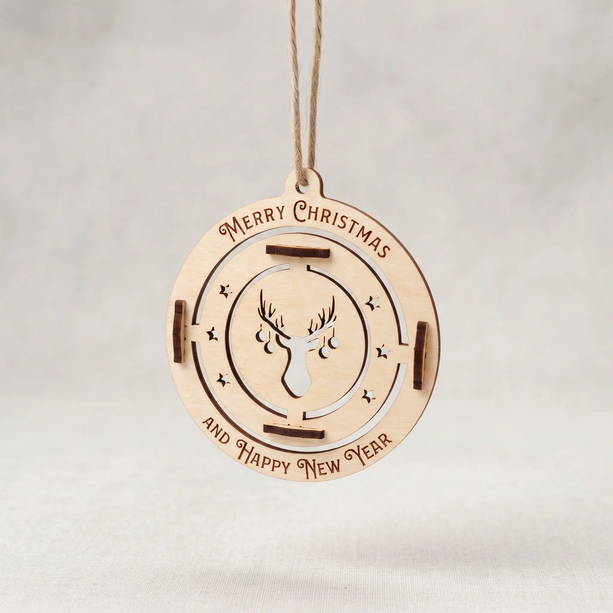 Flat hanging laser cut plywood bauble ornament with stag head cutout and engraved Merry Christmas text on grey.
