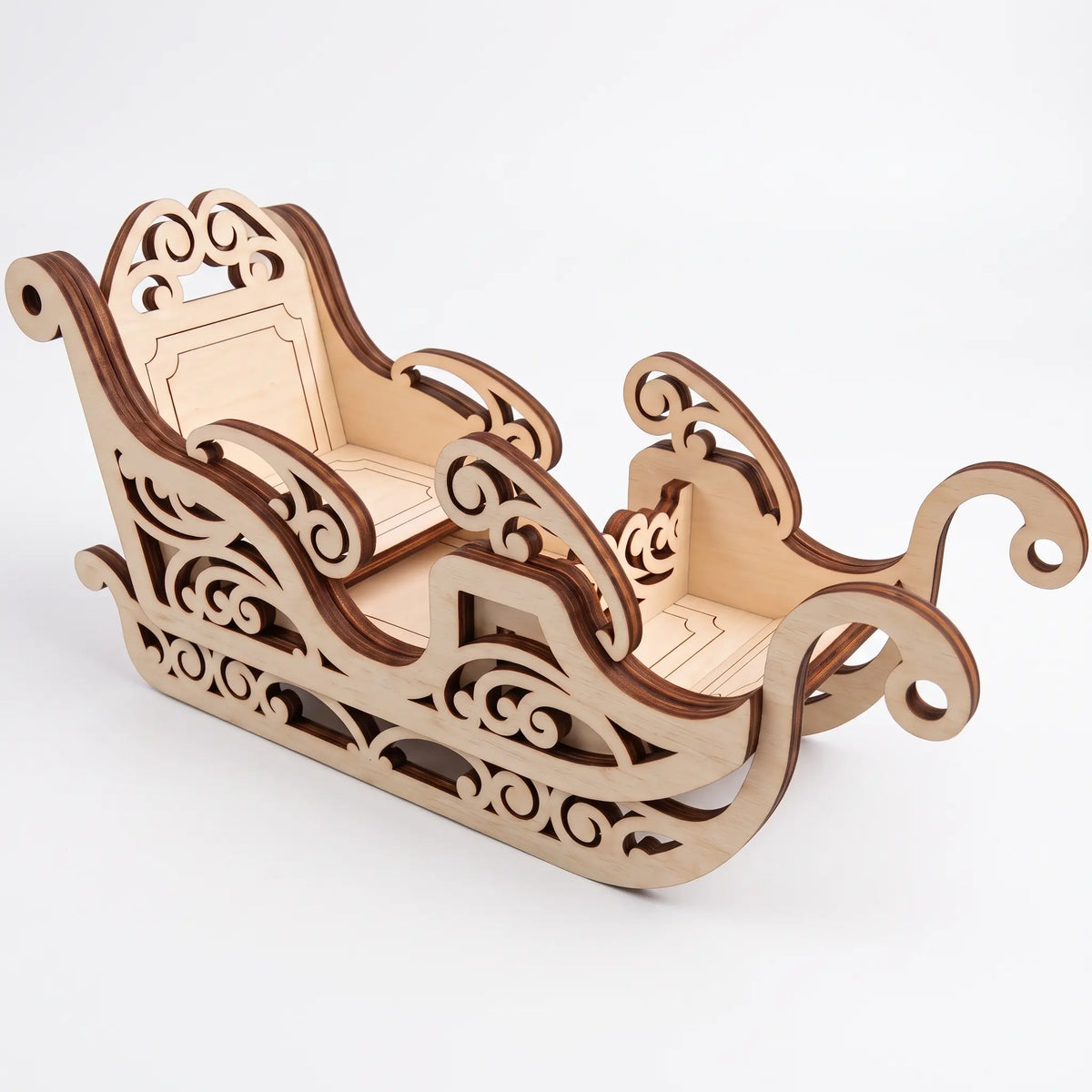 High angle perspective of assembled laser cut plywood Christmas sleigh with curved runners on light base.