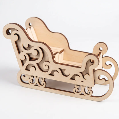 Side view of laser cut plywood miniature holiday sleigh with carved swirl patterns isolated on pure white.
