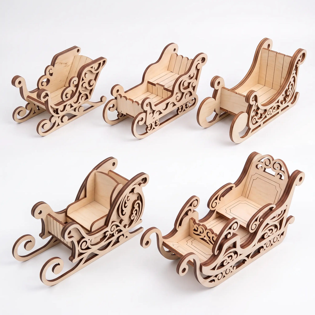 Bundle of five different assembled laser cut plywood Santa sleigh models arranged on clean white background.