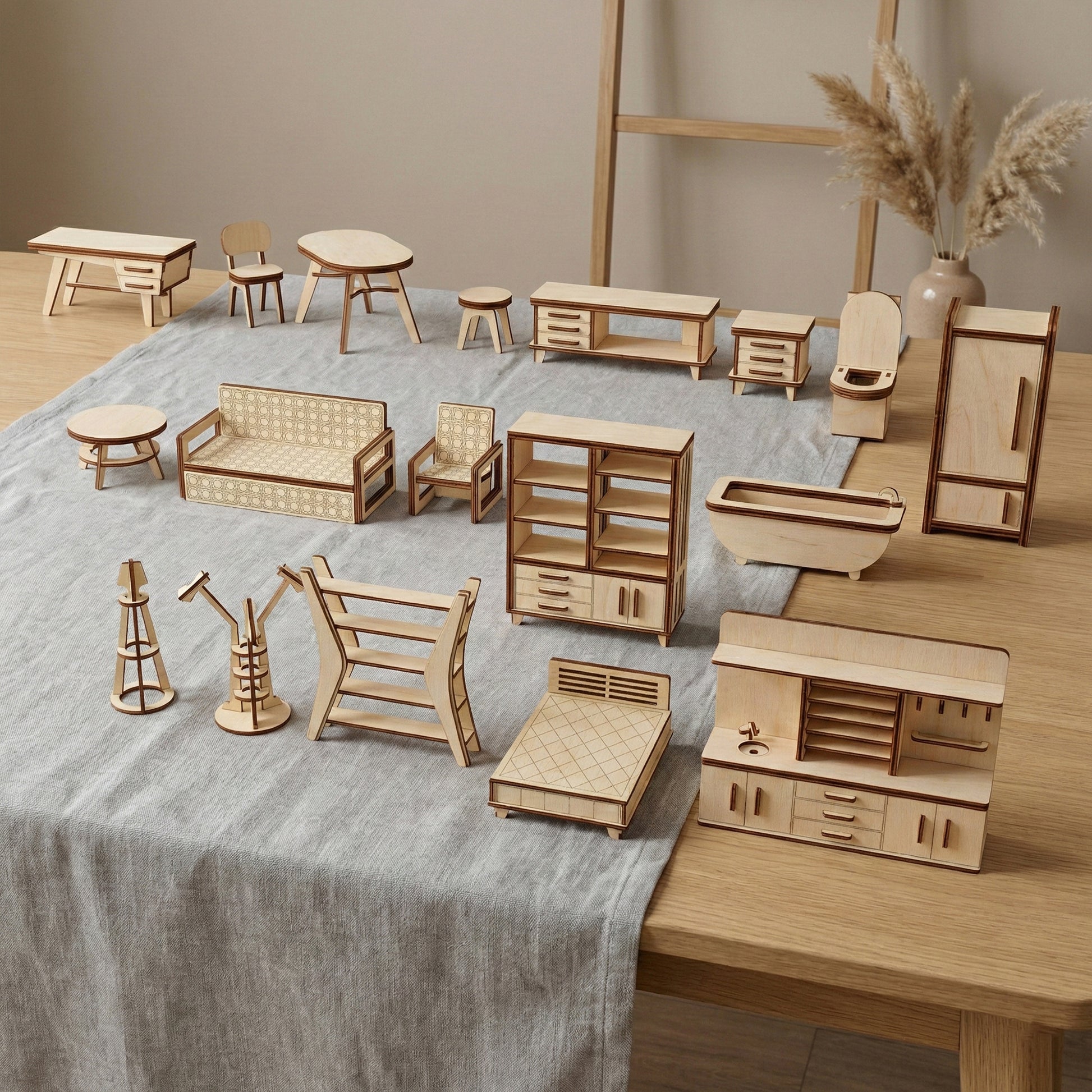 A comprehensive 18-piece dollhouse furniture set made of laser cut plywood. Includes items for the kitchen, bedroom, living room, and bathroom. Arranged on a gray linen cloth, highlighting the natural birch wood and 3D interlocking design.
