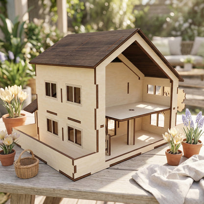 Rear view of a traditional laser cut plywood dollhouse, revealing open interior rooms and a second floor. The house has a steeply pitched dark brown roof and large window cutouts with decorative frames, surrounded by flowers.