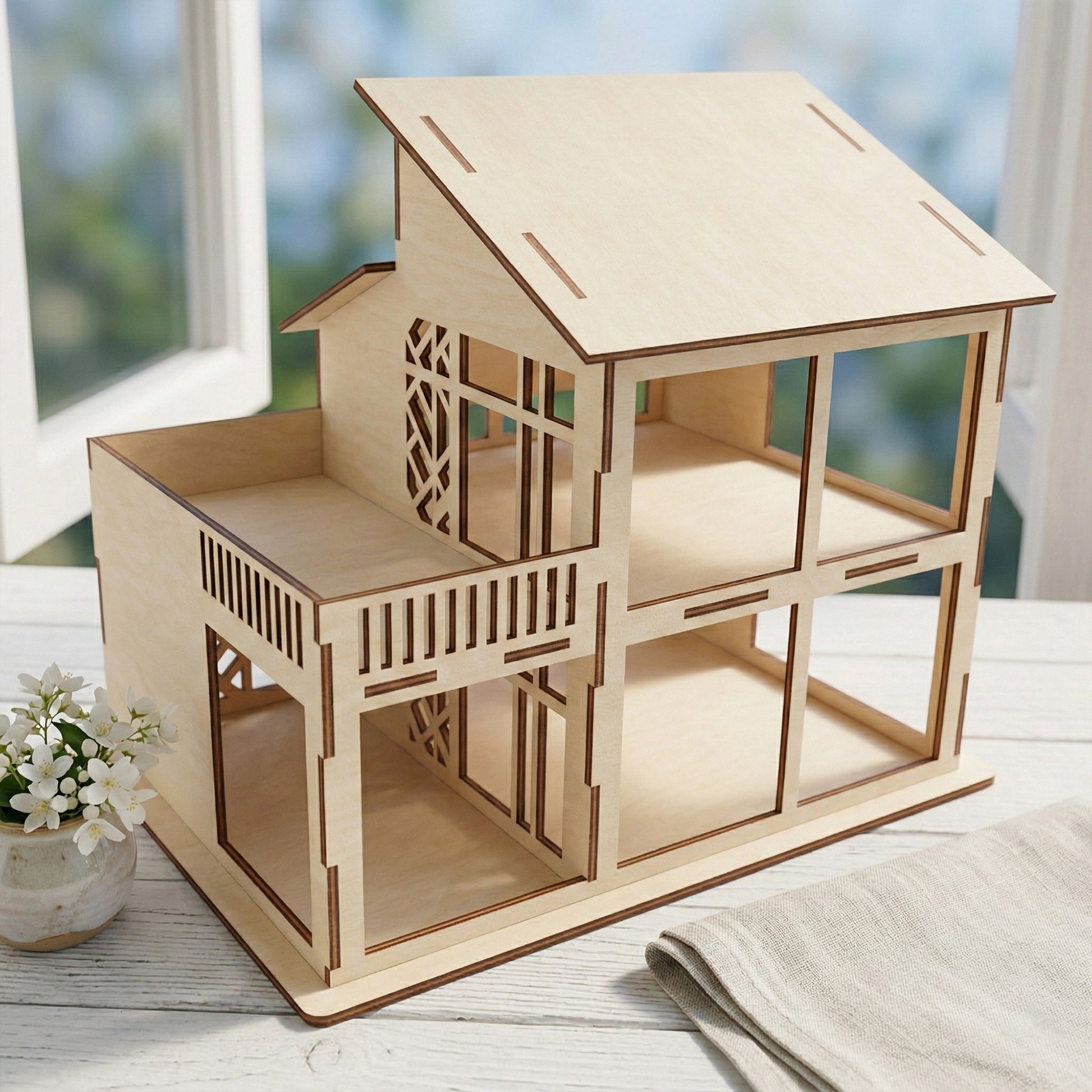 Close-up of the dollhouse balcony and roofline made from laser cut plywood. Displays the delicate geometric patterns on the railings and the clean, scorched edges characteristic of high-quality laser cutting on light wood.