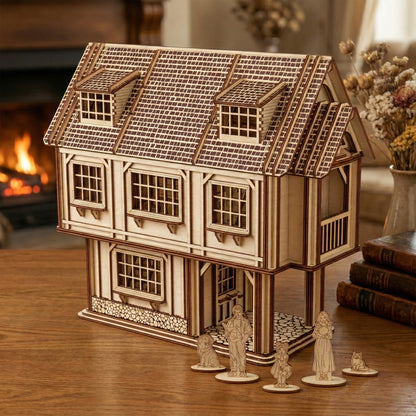 A large two-story Tudor-style dollhouse made of laser cut plywood. Features a textured shingle roof, dormer windows, and a stone-patterned foundation. Shown with wooden family figurines and a dog on a rustic wooden table near a fireplace.