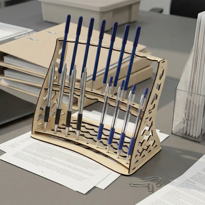 Light wooden laser cut pencil holder with ornate side designs, filled with blue and silver pens, against an office environment with scattered papers.