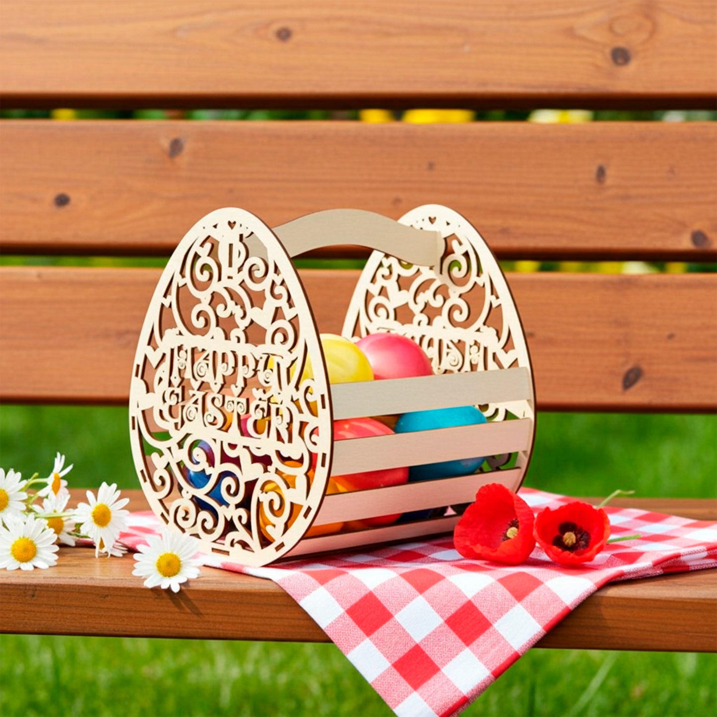Laser cut plywood wooden Easter basket shaped like a decorative egg with "Happy Easter" text cutout, filled with colorful painted eggs and standing on a picnic bench with a red checkered napkin, next to daisies and red poppies