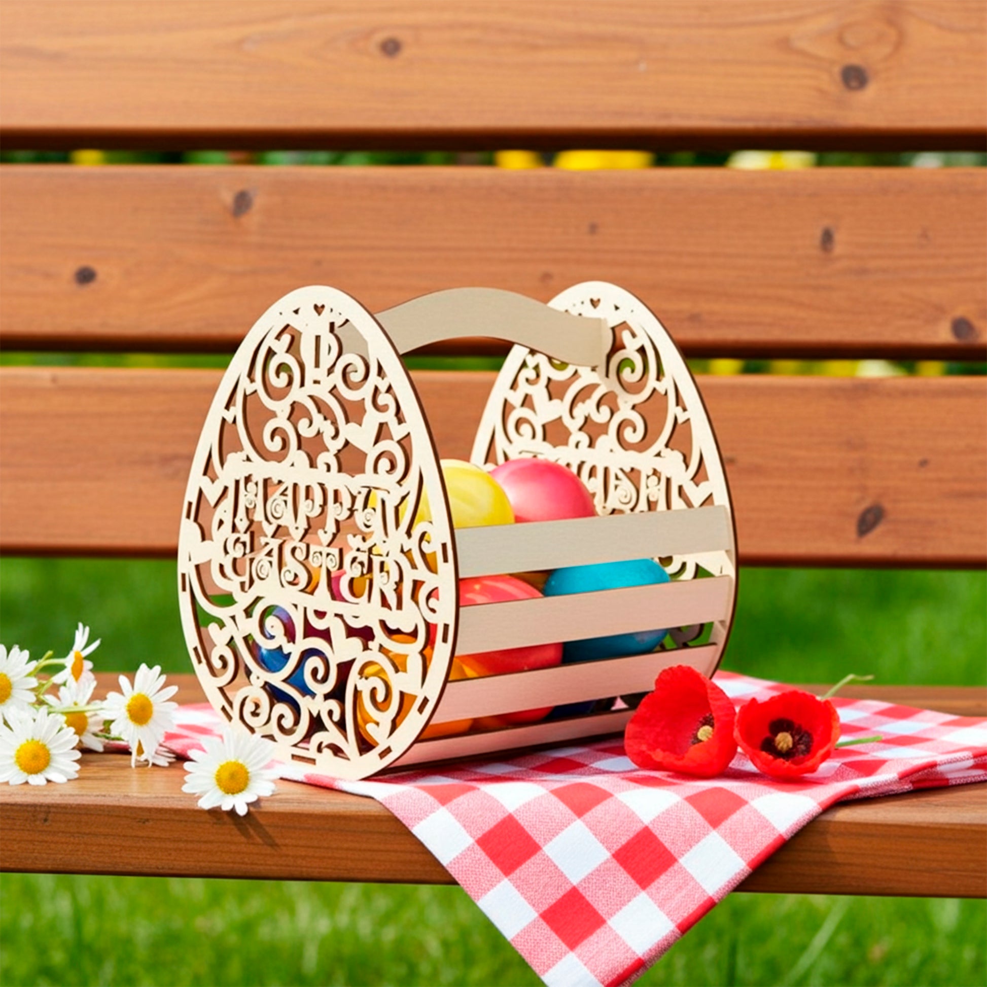 Laser cut plywood wooden Easter basket shaped like a decorative egg with "Happy Easter" text cutout, filled with colorful painted eggs and standing on a picnic bench with a red checkered napkin, next to daisies and red poppies
