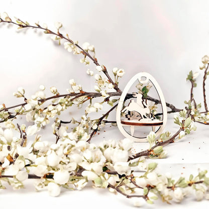 Laser cut plywood wooden Easter egg ornament with a detailed cutout of a bunny in motion, standing above a wooden base, framed by white blooming spring tree branches on a white background.