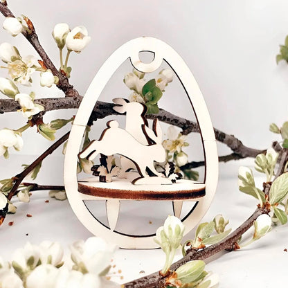 Laser cut plywood wooden Easter egg ornament with a detailed cutout of a bunny in motion, standing above a wooden base, framed by white blooming spring tree branches on a white background.